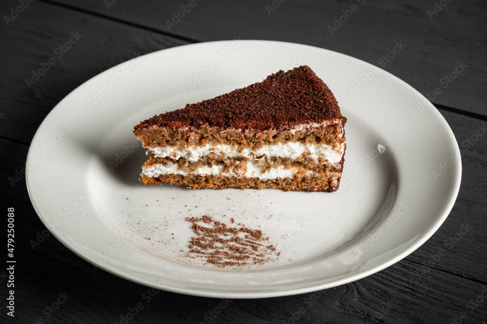 Piece of chocolate cake on a white plate. Black wooden background. Piece of chocolate cake on a white plate. Black wooden background.