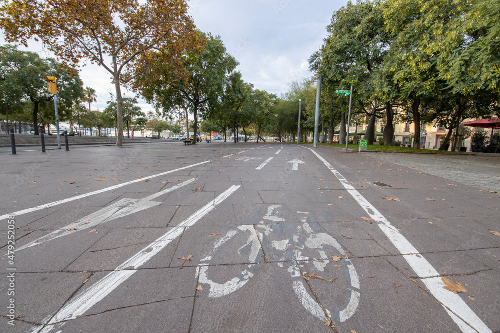 Obraz premium Barcelona, Spain - November 20, 2021: Cycle path in the city center empty due to the coronavirus pandemic. There are few people and vehicles on the street. Empty city