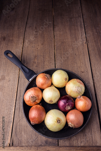 A frying pan with onions on a background of antique board. High quality photo