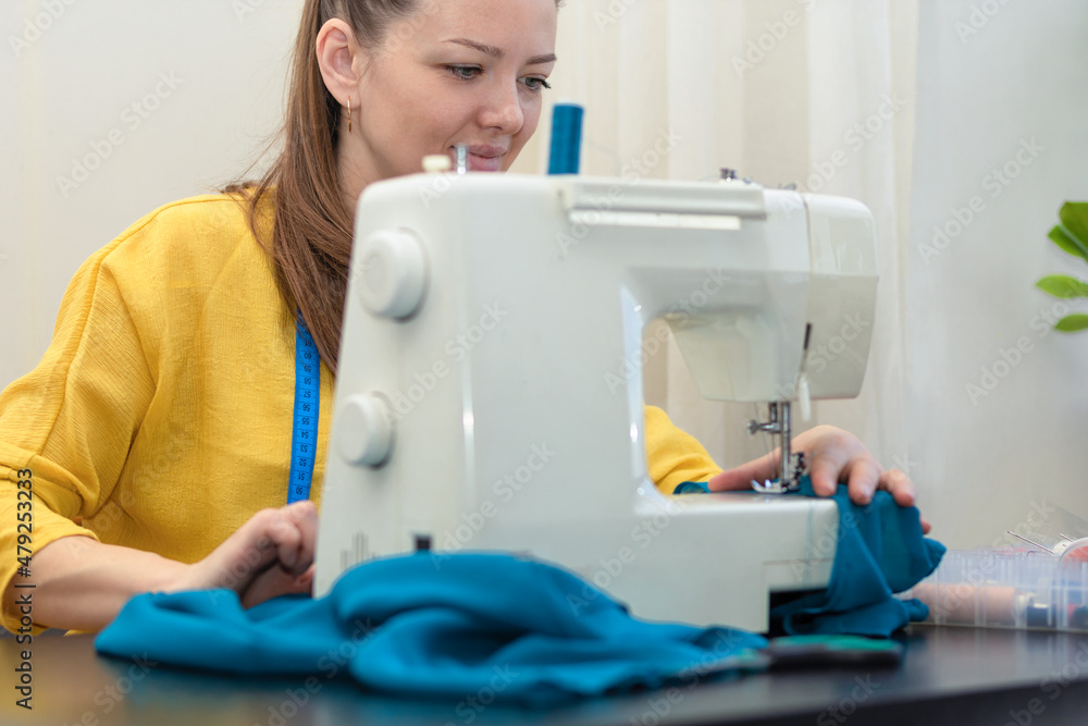 girl fashion designer sew. young dressmaker woman work in modern atelier for sewing machine. female tailor use measuring tape and making garments. Seamstress in workshop.