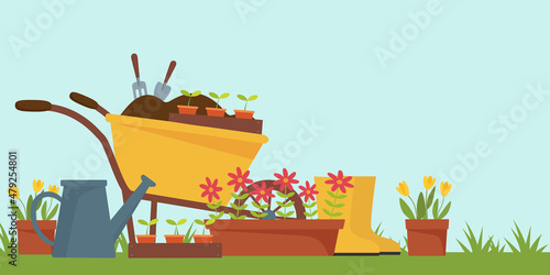 Spring landscape in the garden with green grass, flower, garden wheelbarrow, shovel.