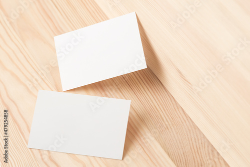 Two white business cards against bright wood  background. Front view.	
