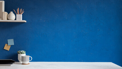 Home office desk with blue wall for mockup or copy space.