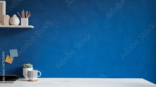 Home office desk with blue wall for mockup or copy space.