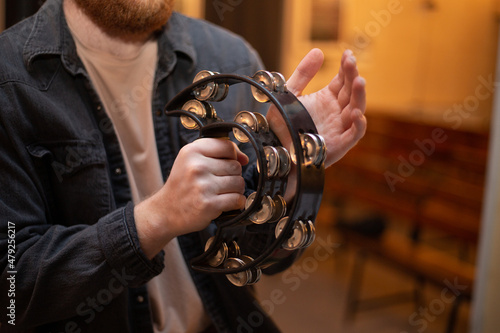 Fotografia, Obraz A young guy with a beard plays the tambourine