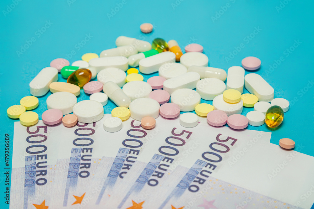 Medicine pills over euro banknotes on a blue background. Covid-19 coronavirus pills are on the euro banknote. The concept of insurance medicine, insurance, high cost, high cost of drugs. Medicine pills over euro banknotes on a blue background. Covid-19 coronavirus pills are on the euro banknote. The concept of insurance medicine, insurance, high cost, high cost of drugs.