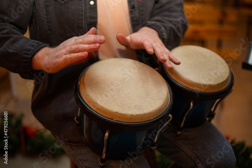 A young guy with a beard plays percussion bongos