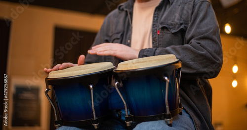 A young guy with a beard plays percussion bongos