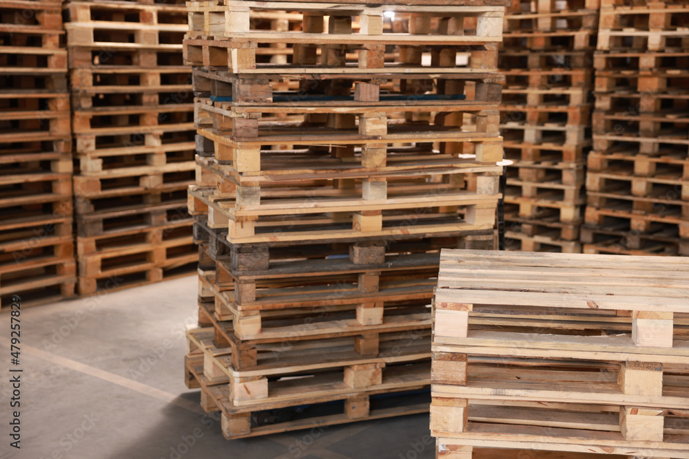 Many empty wooden pallets stacked in warehouse