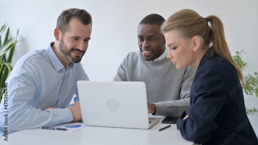 Cheerful Business People Celebrating Success while using Laptop in Office Cheerful Business People Celebrating Success while using Laptop in Office