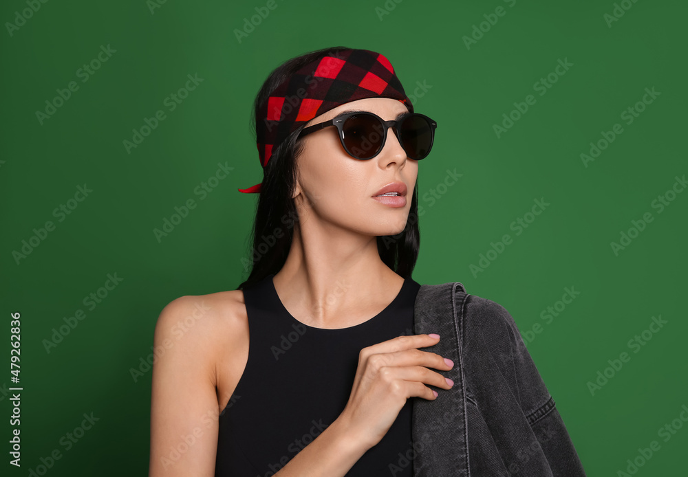 Fashionable young woman in stylish outfit with bandana on green background Fashionable young woman in stylish outfit with bandana on green background