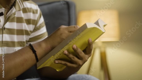 close up shot of unrecognazible young man studying book before going to sleep - concept of novel reading hobby, aspirant and bedtime reading.