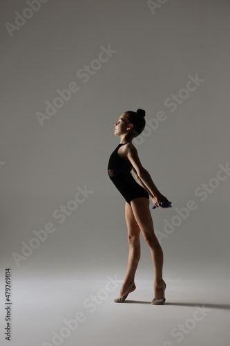 Cute little girl doing gymnastic exercise with rope on white background