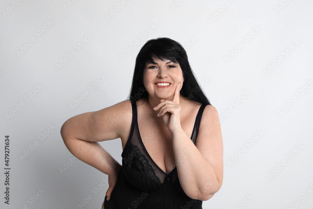 Beautiful overweight woman in black underwear on light background. Plus-size model Beautiful overweight woman in black underwear on light background. Plus-size model