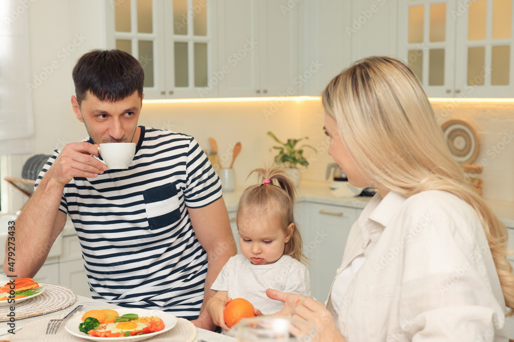 Happy family having breakfast together at table in kitchen Happy family having breakfast together at table in kitchen
