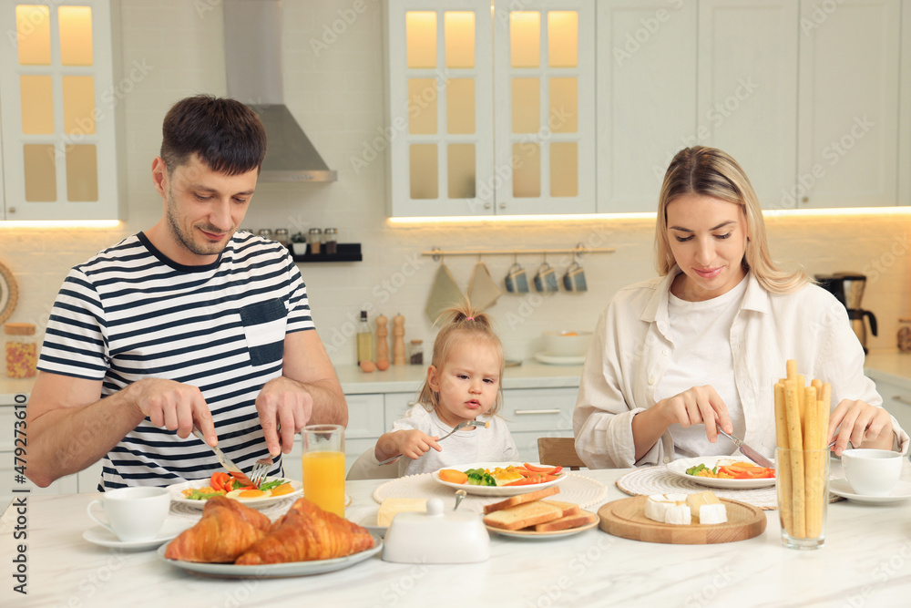 Happy family having breakfast together at table in kitchen Happy family having breakfast together at table in kitchen