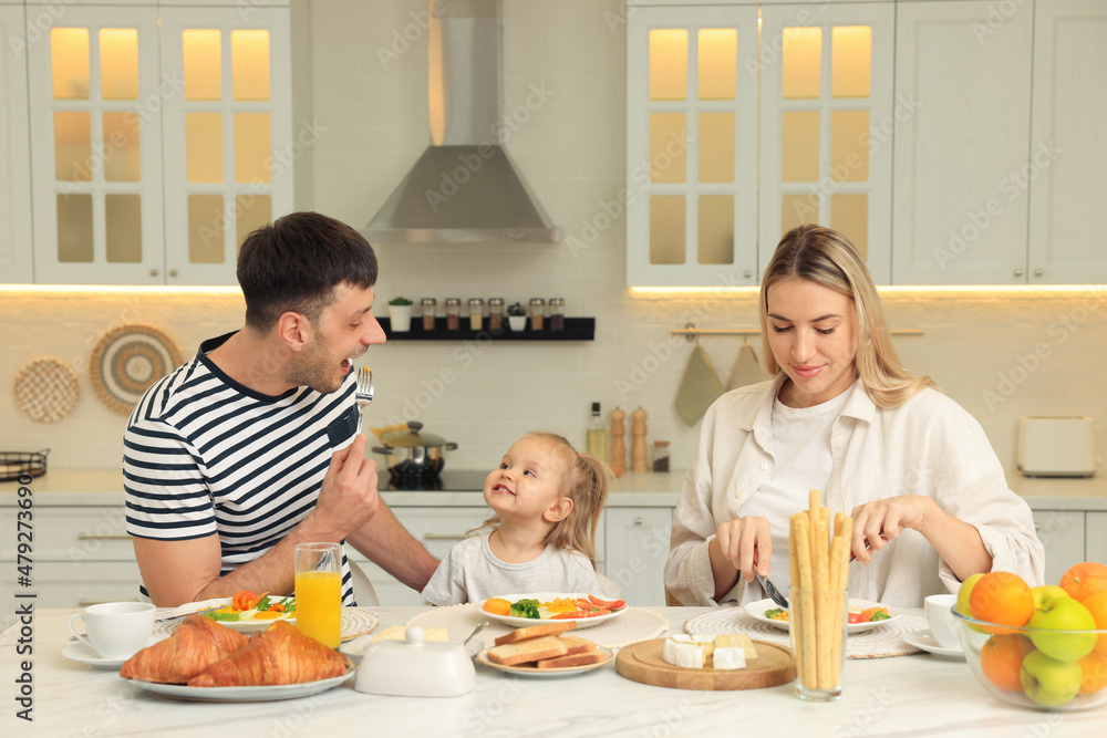 Happy family having breakfast together at table in kitchen Happy family having breakfast together at table in kitchen