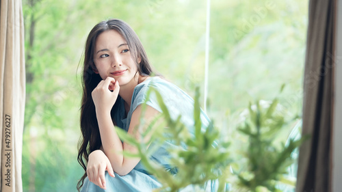 緑の植物を背景にくつろぐ女性　ボタニカルイメージ