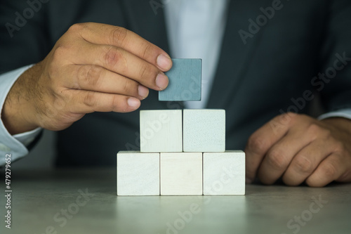 Businessman hand putting and stacking blank wooden cubes on table.