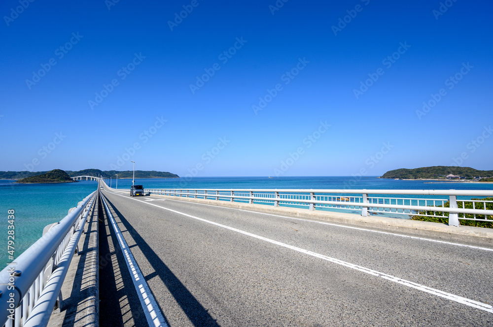 Car crossing Tsunoshima Ohashi Bridge over the emerald green sea