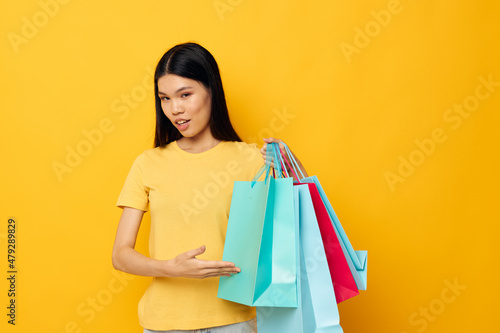 woman with Asian appearance in a yellow T-shirt with multicolored shopping bags studio model unaltered