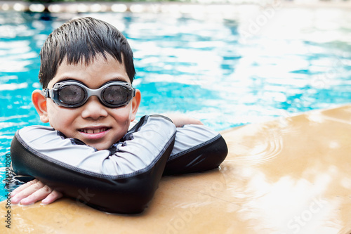 Asian happy kid playing slider in swimming pool