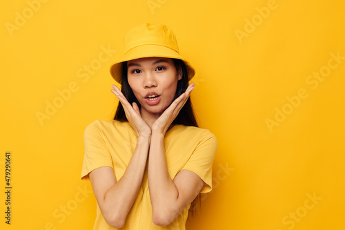 woman with Asian appearance in a yellow t-shirt and hat posing emotions isolated background unaltered