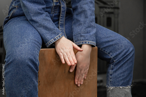 Close-up, a woman in a denim suit plays the cajon.