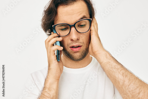 Attractive man in a white T-shirt communication by phone isolated background