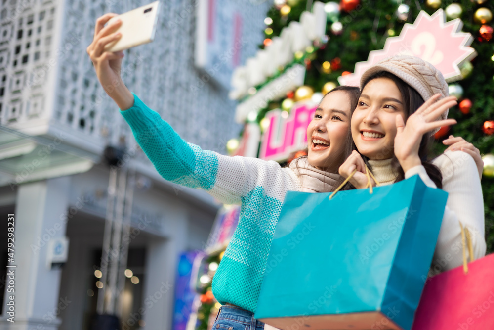 Happy asian woman with shopping bags enjoying in shopping. Young attractive cheerful woman with paper bags and present box after Christmas shopping in mall. Winter sale.