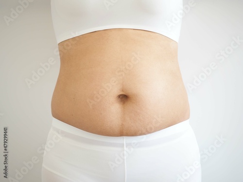 Woman with fat belly, overweight female body on white background. closeup photo, blurred.