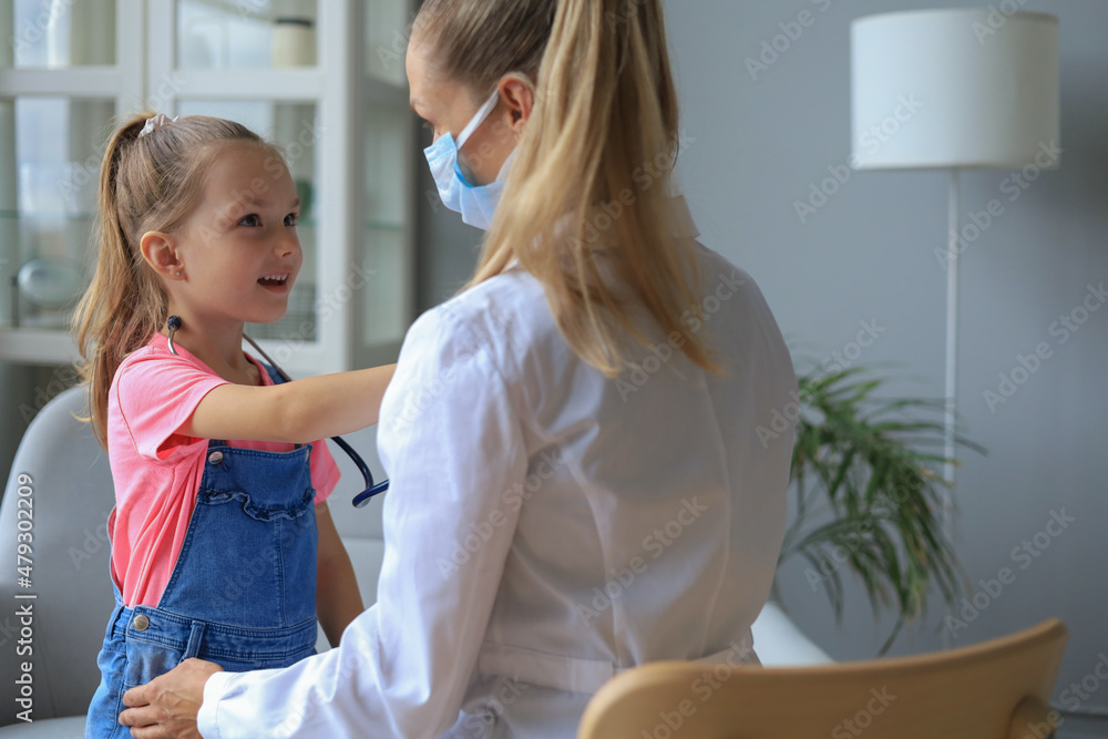 Fototapeta premium Little girl at the doctor for a checkup. Child auscultate the heartbeat of the doctor.