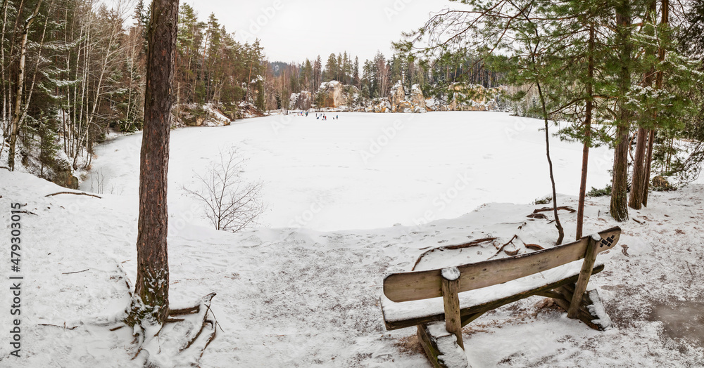 Wooden bench by the frozen blue lake. Winter tracking in popular in Adrspach rocks Wooden bench by the frozen blue lake. Winter tracking in popular in Adrspach rocks
