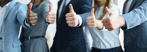 Cropped shot of a group of businesspeople standing in office showing thumb up photo