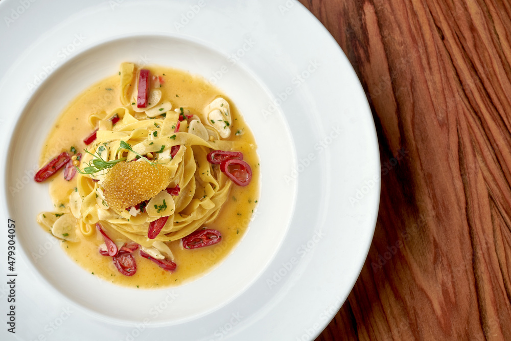 Italian Pepperoncini Pasta with garlic, hot pepper and pike caviar in a white plate on a wooden background Italian Pepperoncini Pasta with garlic, hot pepper and pike caviar in a white plate on a wooden background