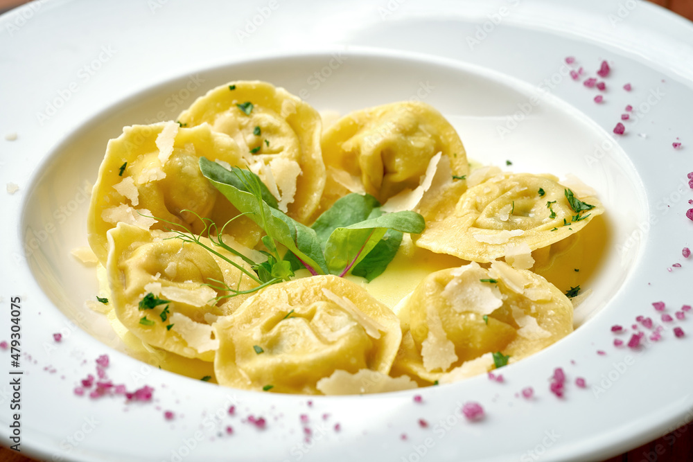 Ravioli with different fillings in sauce and parmesan in a white plate on a wooden background