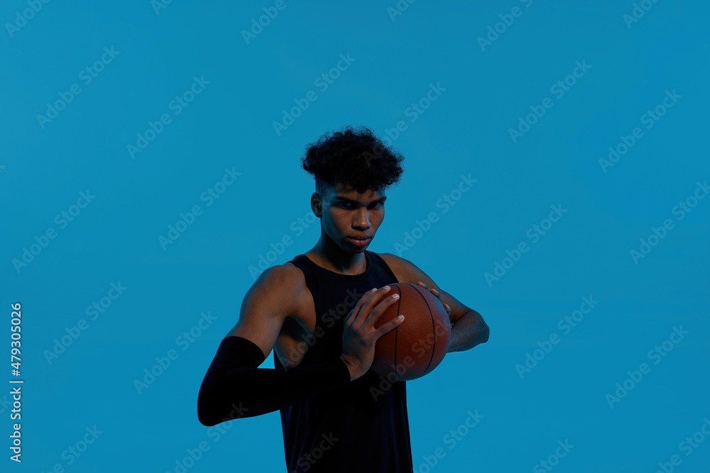 Young serious male player hold basketball ball