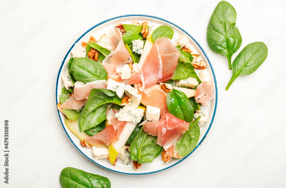 Summer pear salad with jamon, blue cheese, spinach and nuts on white table background, top view, copy space Summer pear salad with jamon, blue cheese, spinach and nuts on white table background, top view, copy space