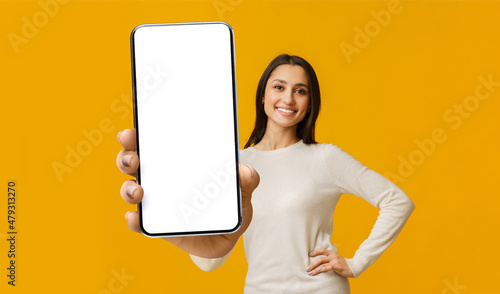 Mobile app mockup. Happy woman showing big cellphone with white blank screen, lady demonstrating space for ad photo