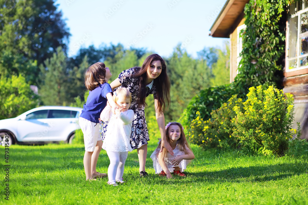 Obraz premium Young large family on a summer morning walk. Beautiful mother with children is playing in the park.