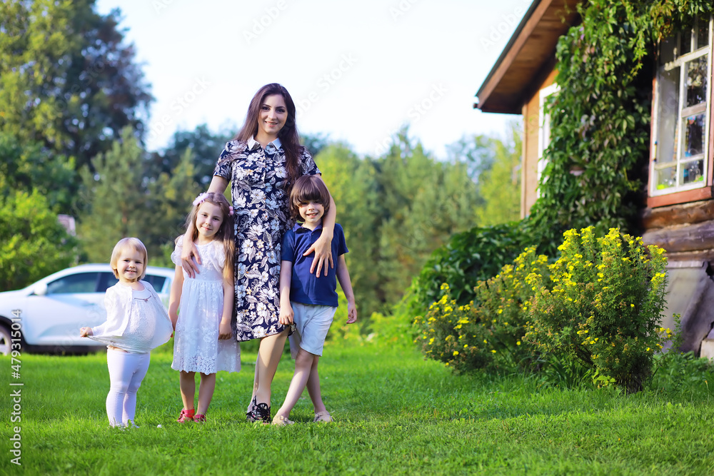 Obraz premium Young large family on a summer morning walk. Beautiful mother with children is playing in the park.