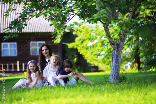 Young large family on a summer morning walk. Beautiful mother with children is playing in the park.