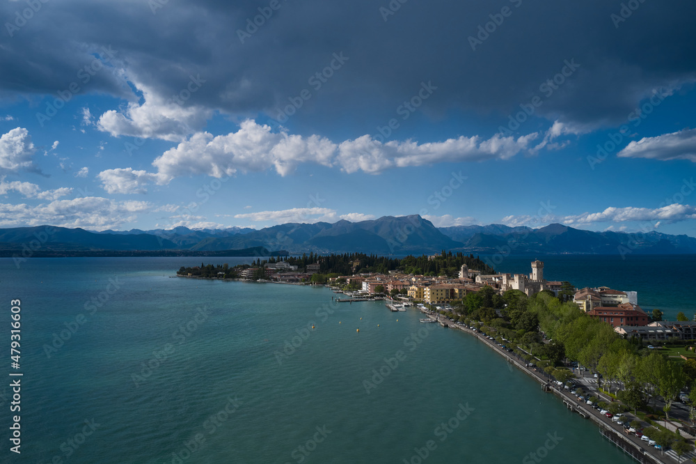 Sirmione, Lake Garda, Italy. Peninsula on a mountain lake in the background of the alps. Aerial view of the island of Sirmione. Panorama of Lake Garda. Castle on the water in Italy.