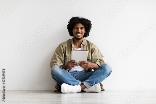 Happy Black Guy Browsing Internet On Digital Tablet While Relaxing On Floor © Prostock-studio