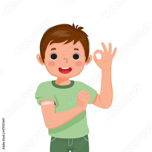 happy little boy showing sticking patch or plaster on his arm after got Vaccine Injection and giving thumb up gestures with smiling facial expression