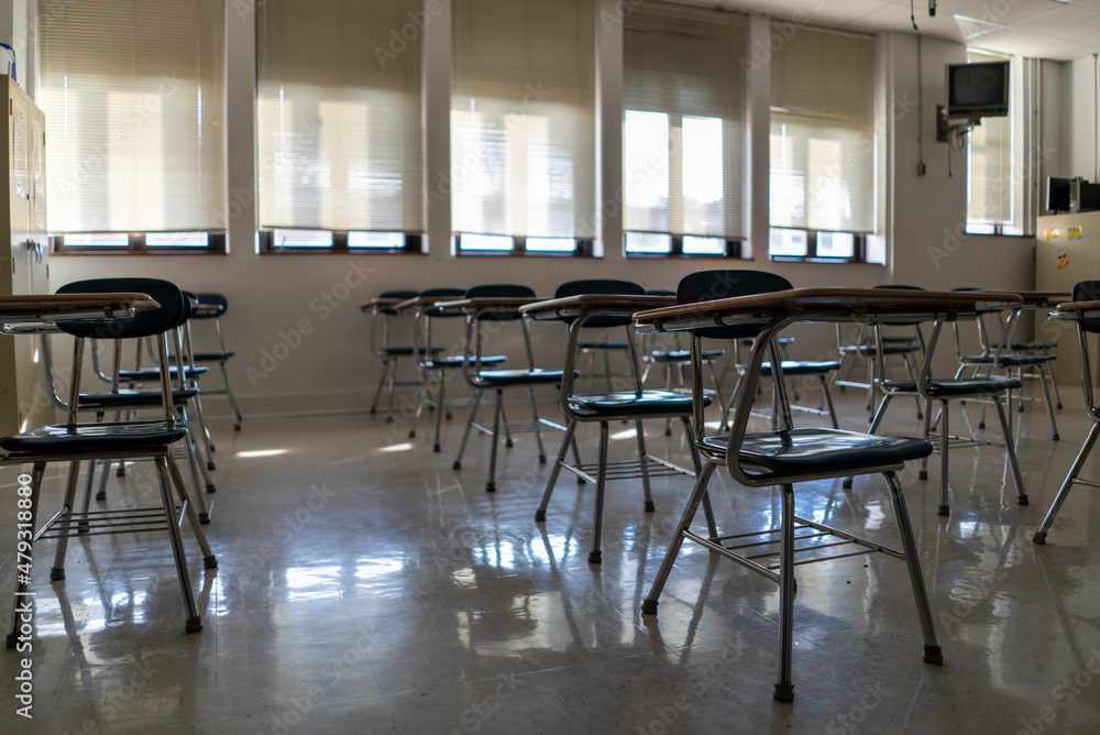 Desks in empty dark high, middle, or elementary school classroom with light coming through windows. Desks in empty dark high, middle, or elementary school classroom with light coming through windows.