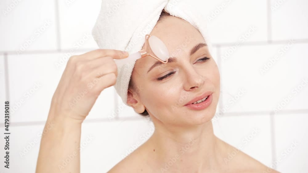 Young woman doing morning routine. Batroom maternity treatment. Health care concept. Female person. Pandemic concept. Pink guasha acupuncture face massage Young woman doing morning routine. Batroom maternity treatment. Health care concept. Female person. Pandemic concept. Pink guasha acupuncture face massage