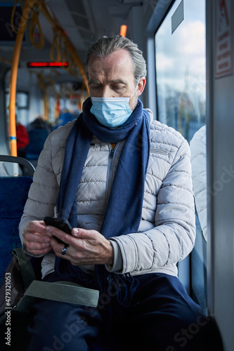 Elderly man with medical protective mask using smartphone