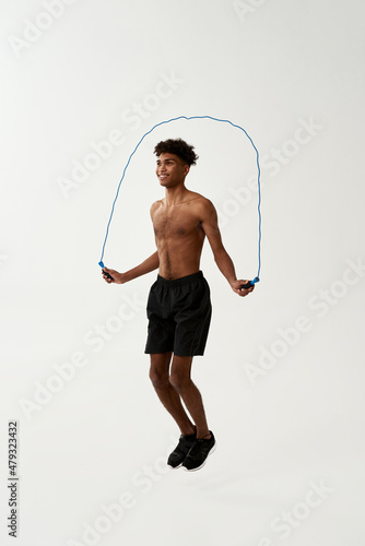 Black smiling sportsman jumping on skipping rope