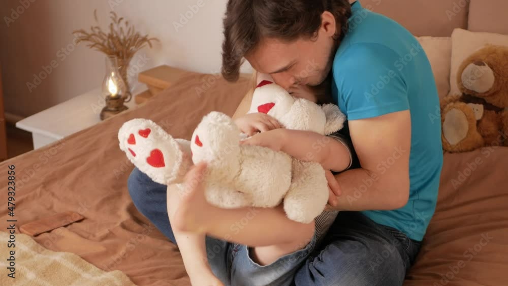 Dad combs his daughter's hair, little baby girl on bed in bedroom. Home morning, lifestyle. Funny and Happy portraits, soft toys. Hugging, loving each other Dad combs his daughter's hair, little baby girl on bed in bedroom. Home morning, lifestyle. Funny and Happy portraits, soft toys. Hugging, loving each other